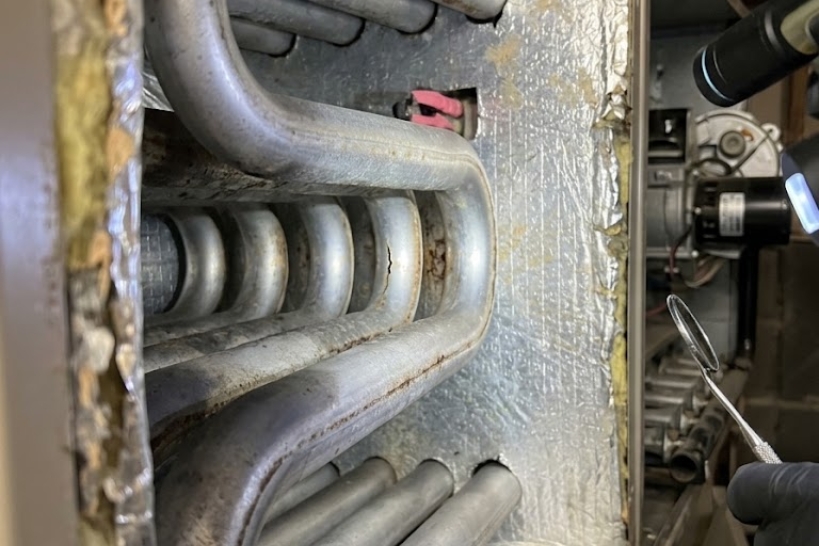 Close-up of a cracked furnace heat exchanger discovered during an HVAC inspection.